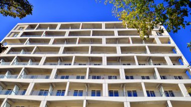 Bereketli yeşil ağaçlarla çevrili ve güneşli bir günde taze bitki örtüsüyle çevrili bir yerleşim yeri. Çağdaş mimari konut kompleksi yeşilliklerle çevrili.