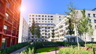 Bereketli yeşil ağaçlarla çevrili ve güneşli bir günde taze bitki örtüsüyle çevrili bir yerleşim yeri. Çağdaş mimari konut kompleksi yeşilliklerle çevrili.