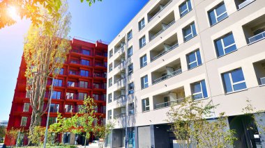 Bereketli yeşil ağaçlarla çevrili ve güneşli bir günde taze bitki örtüsüyle çevrili bir yerleşim yeri. Çağdaş mimari konut kompleksi yeşilliklerle çevrili.