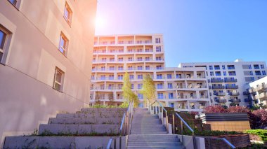 Bereketli yeşil ağaçlarla çevrili ve güneşli bir günde taze bitki örtüsüyle çevrili bir yerleşim yeri. Çağdaş mimari konut kompleksi yeşilliklerle çevrili.