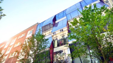 Etrafı yeşil ağaçlarla çevrili cam ofis binası. Çevre dostu ofis binası. Şehrin sürdürülebilir mimarisi ısı karbondioksit azaltıyor modern şehir çevresi.