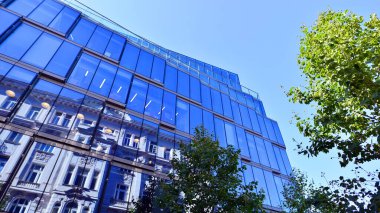 Etrafı yeşil ağaçlarla çevrili cam ofis binası. Çevre dostu ofis binası. Şehrin sürdürülebilir mimarisi ısı karbondioksit azaltıyor modern şehir çevresi.