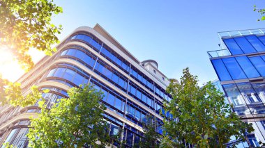 Etrafı yeşil ağaçlarla çevrili cam ofis binası. Çevre dostu ofis binası. Şehrin sürdürülebilir mimarisi ısı karbondioksit azaltıyor modern şehir çevresi.