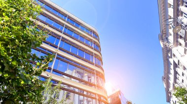 Etrafı yeşil ağaçlarla çevrili cam ofis binası. Çevre dostu ofis binası. Şehrin sürdürülebilir mimarisi ısı karbondioksit azaltıyor modern şehir çevresi.