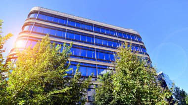Etrafı yeşil ağaçlarla çevrili cam ofis binası. Çevre dostu ofis binası. Şehrin sürdürülebilir mimarisi ısı karbondioksit azaltıyor modern şehir çevresi.