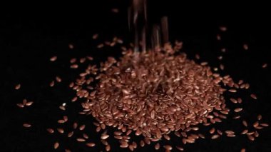 Keten tohumları siyah arkaplana düşer.