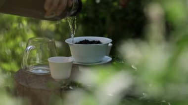 Sıcak su bir termostan geleneksel Çin çay takımına dökülüyor. Sabahları huzurlu bir bahçe ortamında..