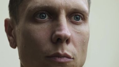 Yağmurun altında üzgün ve bitkin bir adamın yüzüne damlayan yağmur damlaları yalnızlığı ve hayal kırıklığını gösteriyor.