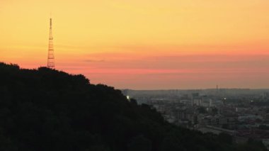 Kyiv 'in canlı bir günbatımında panoramik manzarası, sıcak akşam ışığı ile aydınlanan şehir silüeti..