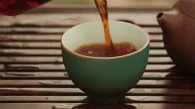 Bir kaseye çay dolduruyorum. Çin çay seremonisi. Seramik çaydanlık. Yakın plan.