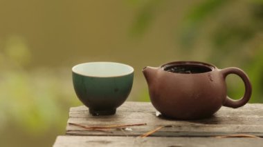 Çamur çaydanlığı seramik bir fincana çay döküyor..