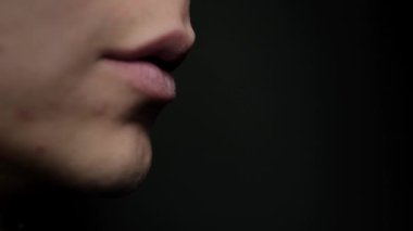 Adam bir sigara tüttürüyor. Siyah bir arkaplana yaklaş. Nikotin bağımlılığı konsepti. Dudaklardan duman çıkar..