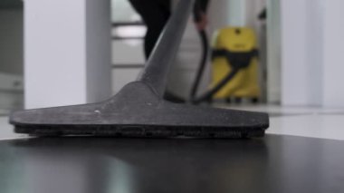 Bir kadının mutfak zeminini süpürürken, siyah ve beyaz fayanslardan toprağı temizlerken yakın plan çekimleri..