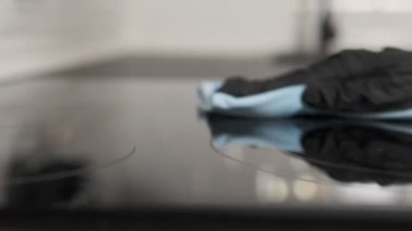 Temizlikçi mutfak fırınını mavi bir bezle temizliyor, yemek alanında temizlik ve düzeni teşvik ediyor..