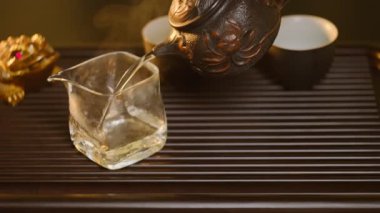 Sıcak çay, dekoratif demir çaydanlıktan geleneksel çay tepsisindeki cam sürahiye dökülür ve buhar yükselir..