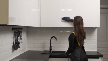 Modern minimalist mutfakta mutfak cephelerini temizleyen profesyonel temizlikçilerin yakın çekimi..