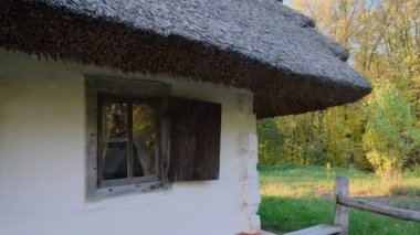 Yeşil orman ortamında sazdan çatısı ve ahşap panjurları olan kır evi, kırsal çekiciliği çağrıştırıyor..