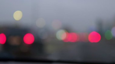 Bulanık araba ışıkları sisli bir akşam trafiğinde gri bir zemin üzerinde renkli bokeh oluşturur.