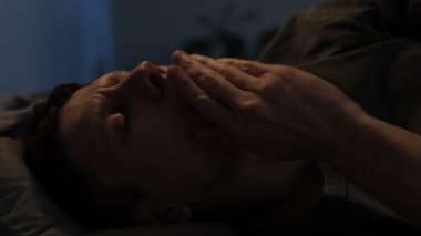 Yataktaki genç adam esniyor, ışığı söndürüyor ve yan yatıp dinlenmeye hazırlanıyor..