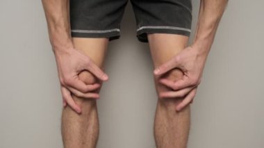 Bir adam iki eliyle dizlerine masaj yapar, eklem ağrısı ve önleyici bakımı vurgular..