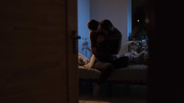 Genç bir çift sıcak bir akşam ışığı altında bir yatakta oturur, romantik bir şekilde kucaklaşır ve aşkı hissederler..
