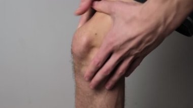 Bir adam iki eliyle dizlerine masaj yapar, eklem ağrısı ve önleyici bakımı vurgular..