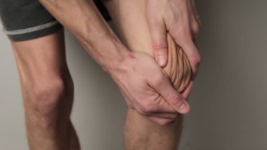 Bir adam iki eliyle dizlerine masaj yapar, eklem ağrısı ve önleyici bakımı vurgular..