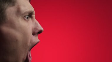 Adamın kızgın yüz ifadesine yaklaş. Kırmızı parlak arkaplan.