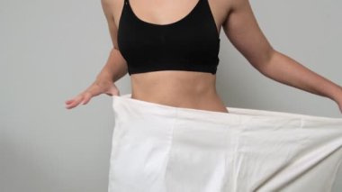 Kilo kaybı ve fitness hedeflerini temsil eden, büyük beden pantolonlu zayıf bir kadın..