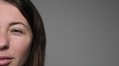 Görünür yüz hatlarıyla gözlerini kısarak odaklanan ya da rahatsızlık veren bir kadının yakın çekimi.. 