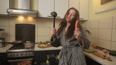 Aktif genç bir kadın mutfakta yemek hazırlıyor, dans ediyor, hobi yapıyor, keyfi yerinde. Yüksek kalite 4k görüntü