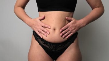 Tombul bir kadın karnını çimdikler. Kilo verme ve kilo verme kavramı.