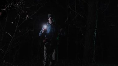 Karanlık bir ormanda yalnız bir adam yolunu bulmak için el feneri kullanıyor. Yoğun ağaçlarla çevrili. Gizem, korku ve hayatta kalma hissi uyandırıyor..