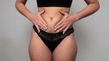 Aynanın önündeki kadın vücuduna bakıyor. Aşırı göbek yağı, sağlıksız yaşam tarzı, diyet konsepti.