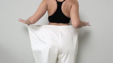 Kilo kaybı ve fitness hedeflerini temsil eden, büyük beden pantolonlu zayıf bir kadın..
