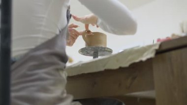 Çömlekçilik kursunda kilden kupa yapan bir kadının yakın çekimi. Çamurdan bir kupa yaratma süreci. Yaratıcı hobi