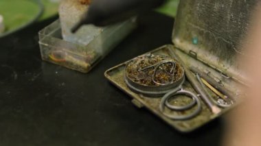 Elektronik devre kartı üzerinde çalışırken duman çıkaran bir lehim demirinin yakın plan görüntüsü. Bileşen onarımı için lehimleyici. Arkaplan elektronik araçlar ve ekipmanlarla bulanık çalışma alanı
