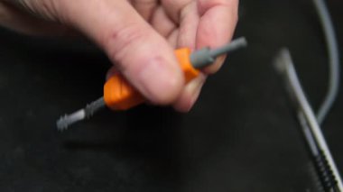 Elektrikçi ustası kablolardan yalıtım malzemesi alıyor. Küçük elektronik tamirat, yalıtım katmanını kablodan çıkarıp tamir etmek, yakın plan.