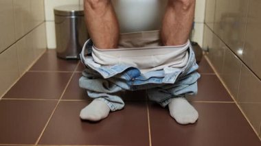 Bir erkeğin bacakları, süreci tamamladıktan sonra kabızlıktan kurtuluşun sembolü olarak mutlu bir şekilde dans eder..