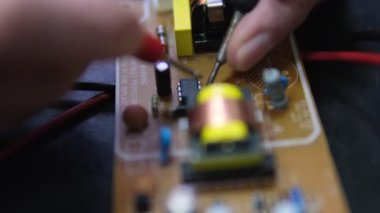 Bir elektrikçi voltajı ölçmek ve devre kartındaki elektronik bileşenleri kontrol etmek için çoklu metre kullanır.