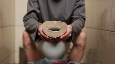 Tuvalet kağıdıyla tuvalette oturan adam kabızlık, ishal, karın ağrısı ya da kramplardan muzdarip. Yemek borusu sorunu belirtileri