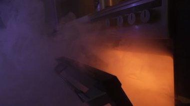 Mutfaktaki fırından çıkan duman. Yanmış yemek. Fırının bulanık görüntüsü ve kapı koluna odaklanma. Yangın güvenlik tehlikesi.