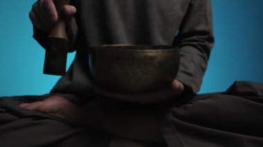 Evde lotus pozisyonunda oturan ve şarkı söyleyen bir adam. Rahatlama ve meditasyon. Ses terapisi, alternatif tıp. Budist şifa uygulamaları.