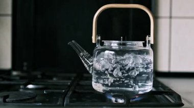 Gaz sobasında bardaktan kaynar su görünür köpükler ve mutfak ortamında buhar..