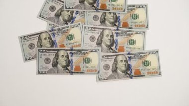 Dolar banknotları teker teker ortaya çıkıyor. Beyaz arka planda 100 dolarlık banknotlar. Banknotlar görünür ve kaybolur. Hareketi Durdur. Finansal zenginlik, bankacılık, ekonomik refah. Enflasyon ve deflasyon.
