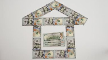 Emlak yatırımı. Bir evin finansal animasyonu, ev sigortasını ve ipotek kredilerini sembolize eden 100 dolarlık banknotlardan oluşur. Emlak teminatı.