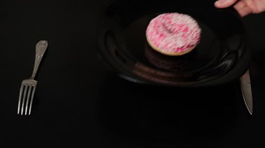 Elle tabağa pembe kremalı donut koyup çatal ve kaşığın yanına koyuyorsun. Tatlıyı espritüel bir şekilde restoran ortamında sunuyorsun.