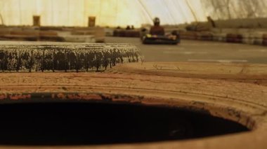 Arka planda kart yarışçısının bulanıklaştığı güvenlik bariyeri olarak eski lastiklerin yakın plan görüntüsü.
