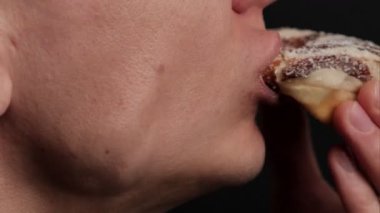 Çikolata kaplı donutu hindistancevizi taneleriyle ısıran, ağız ve el ele hamur işlerine odaklanan, hoşgörü, arzu ve tatlı tatlı yemenin zevkini ifade eden bir adamın yakın çekimi..