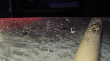 Yakınlarda büyük bir tahta yarasayla tozlu yüzeye saçılmış kırık cam kırıklarının yakın plan görüntüsü, yakın zamanda meydana gelen yıkım ya da agresif patlamayı simgeliyor..